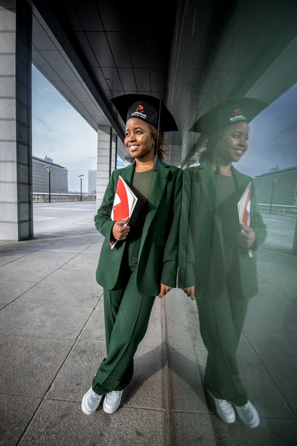 une femme en robe de fin d’études et casquette détenant un diplôme