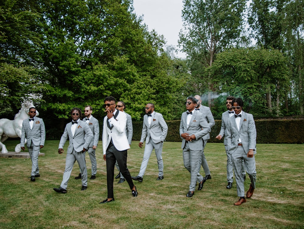 a group of men in suits walking on grass