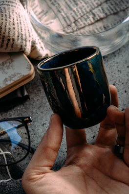 A terracotta ceramic cup on a cream ivory linen cloth beside a notebook with handwritten notes about the collections