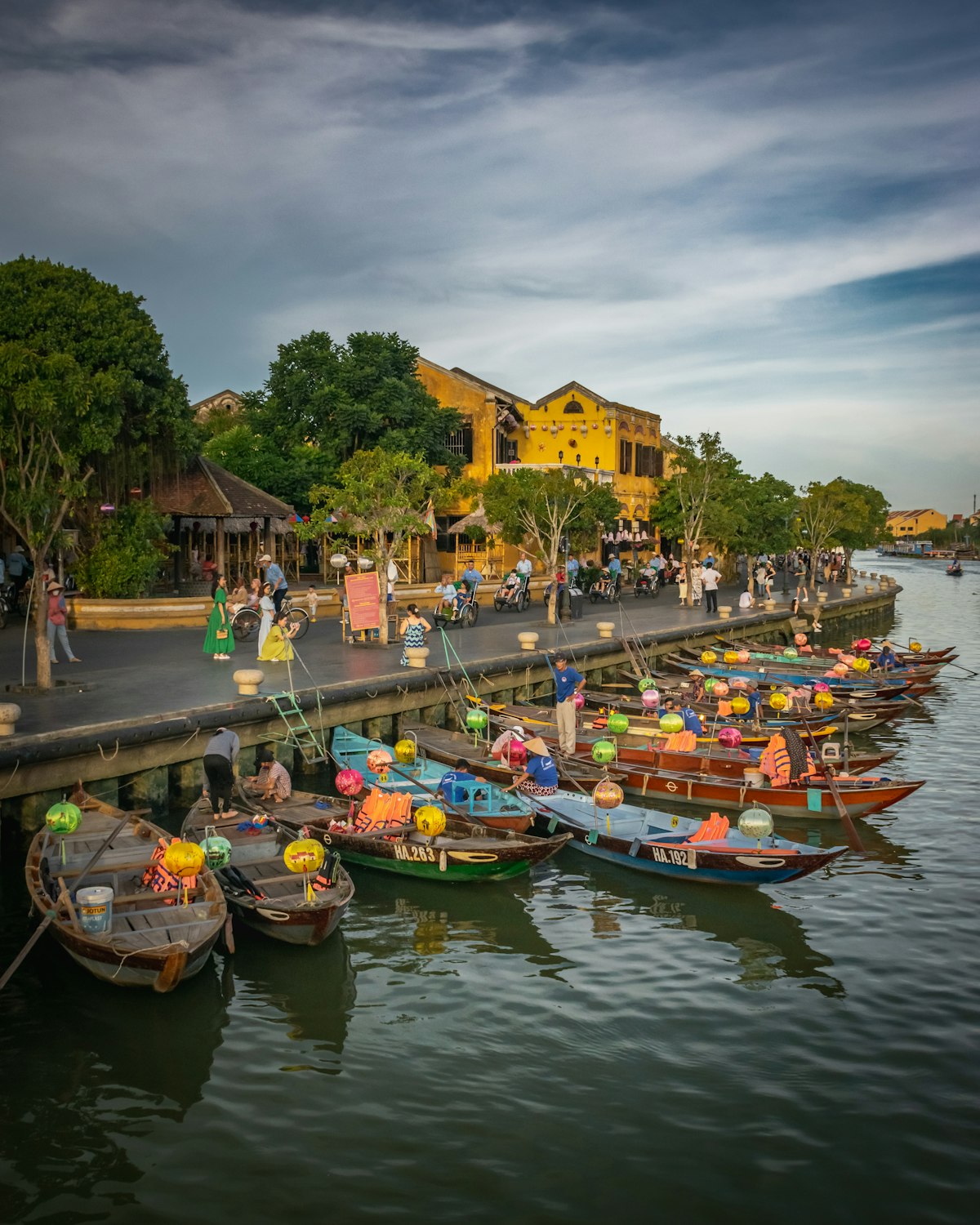 Hoi An An Hoi Peninsula — lantern boats moored on the Thu Bon River at dusk with the Ancient Town glowing behind
