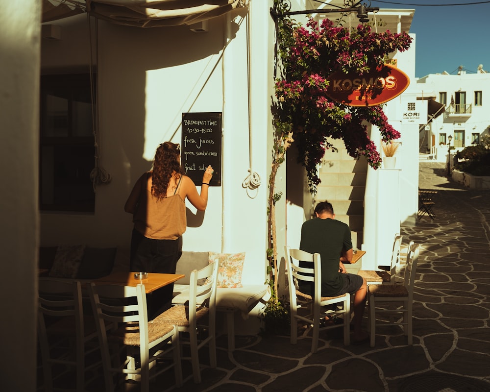 a man and woman sitting at a table outside a restaurant