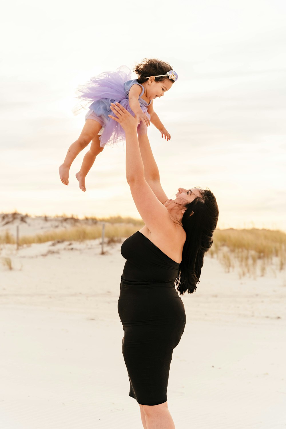 a person holding a baby on the back on a beach