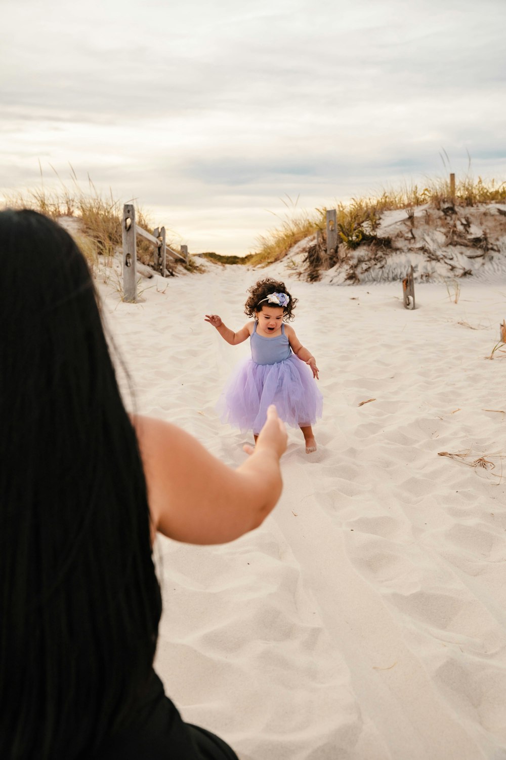 a woman holding a child on a beach