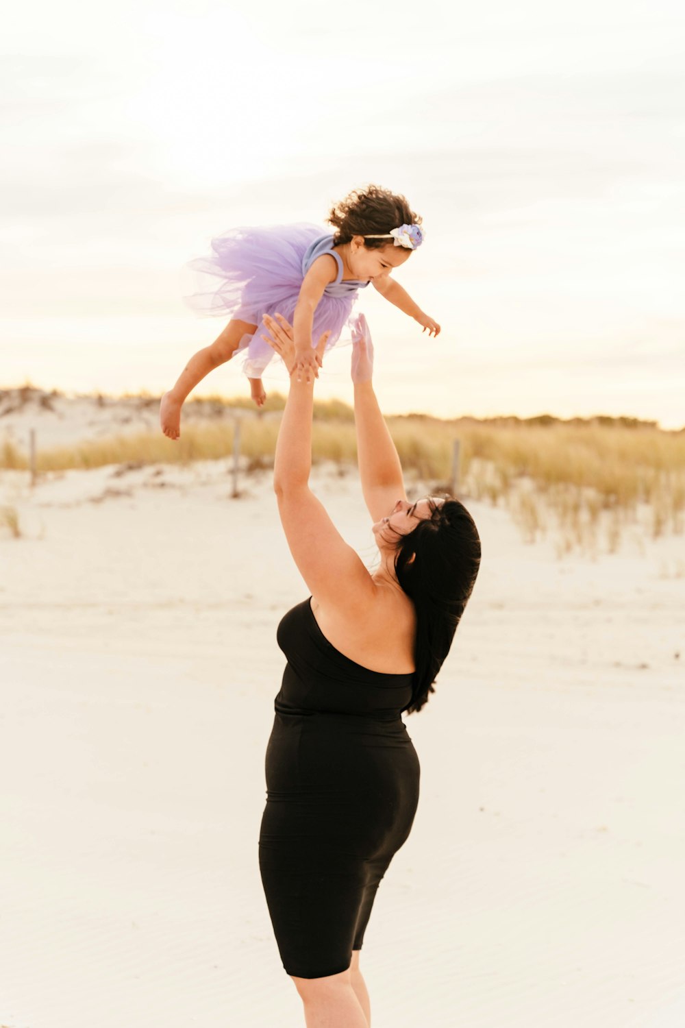 a person holding a baby on the back on a beach