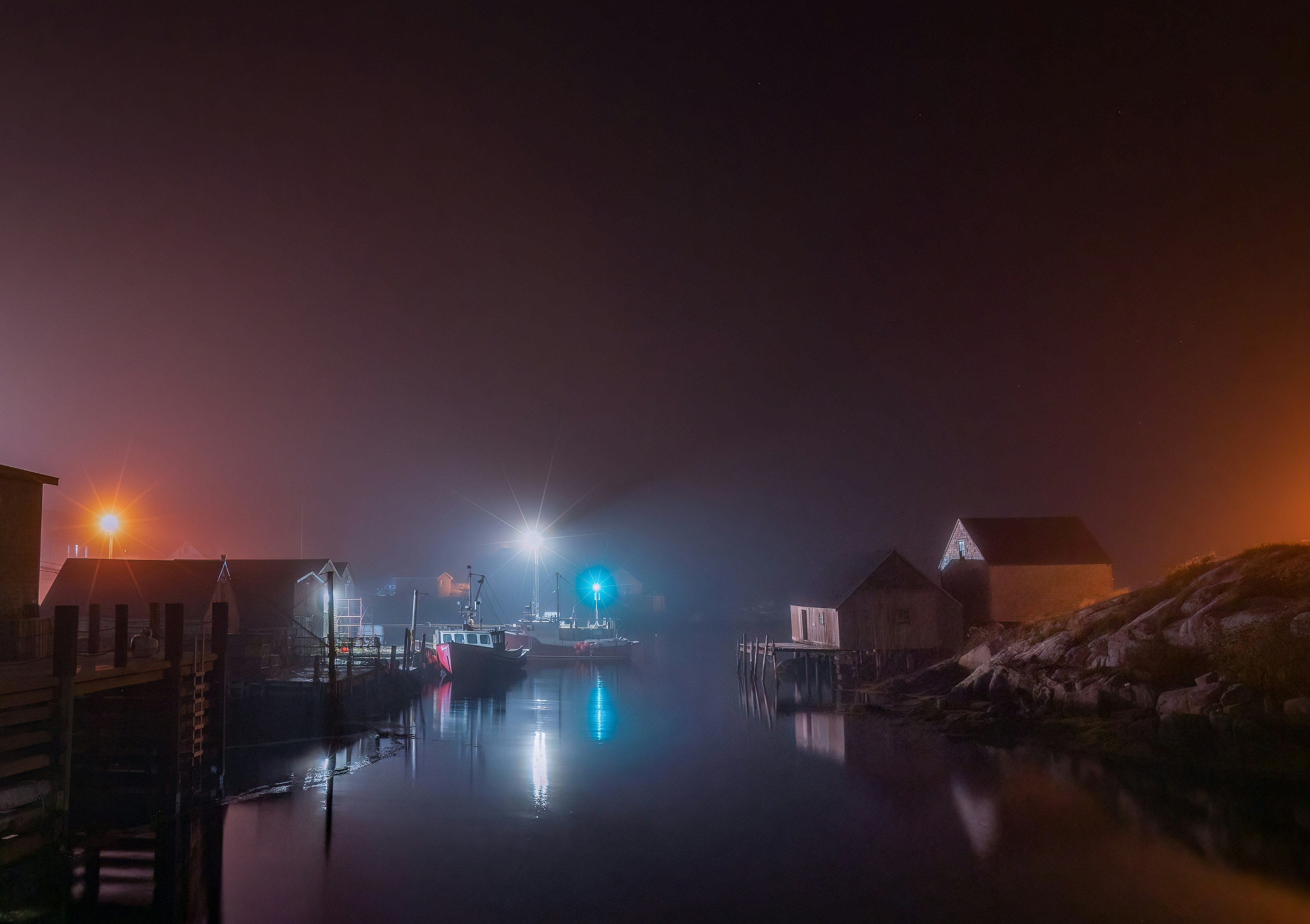 a body of water with buildings along it and a bridge with lights