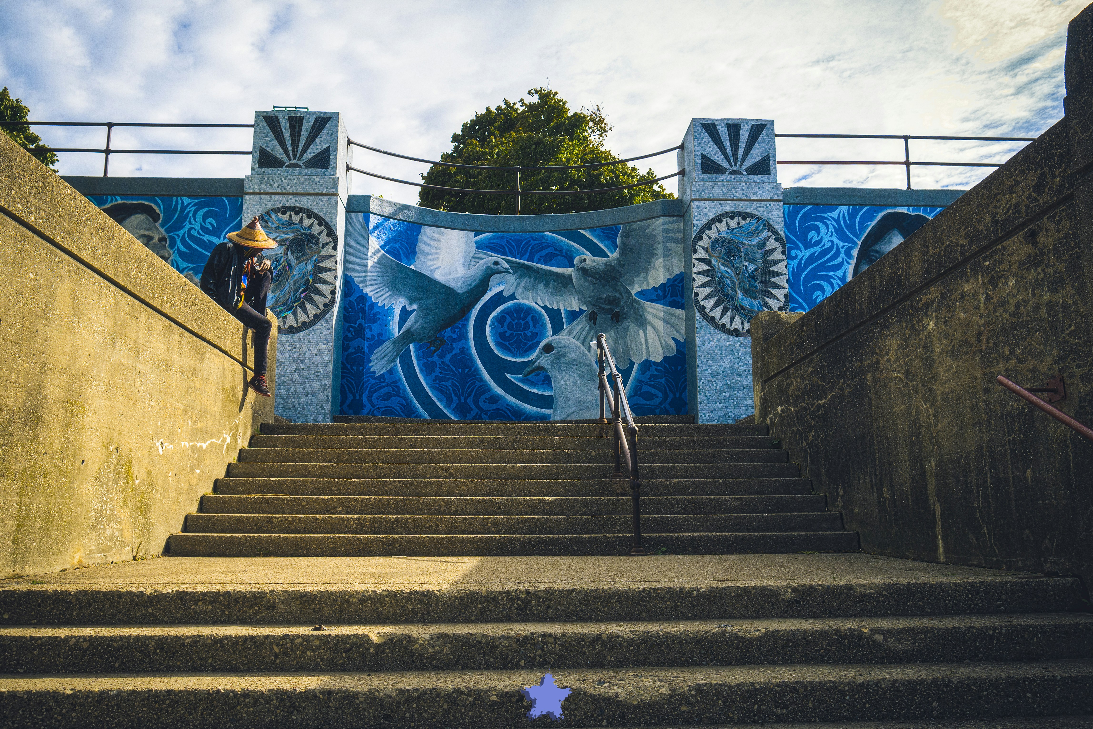 a set of stairs leading up to a wall with art on it