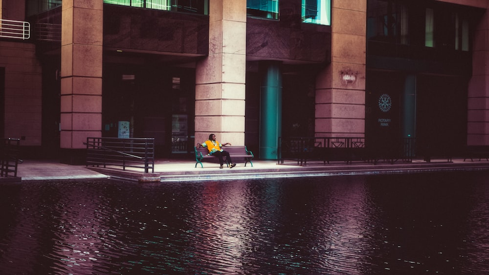 a couple of people sitting on a bench by a body of water
