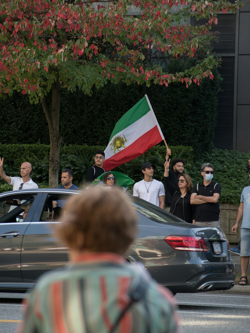 a group of people standing on the side of a road holding a flag