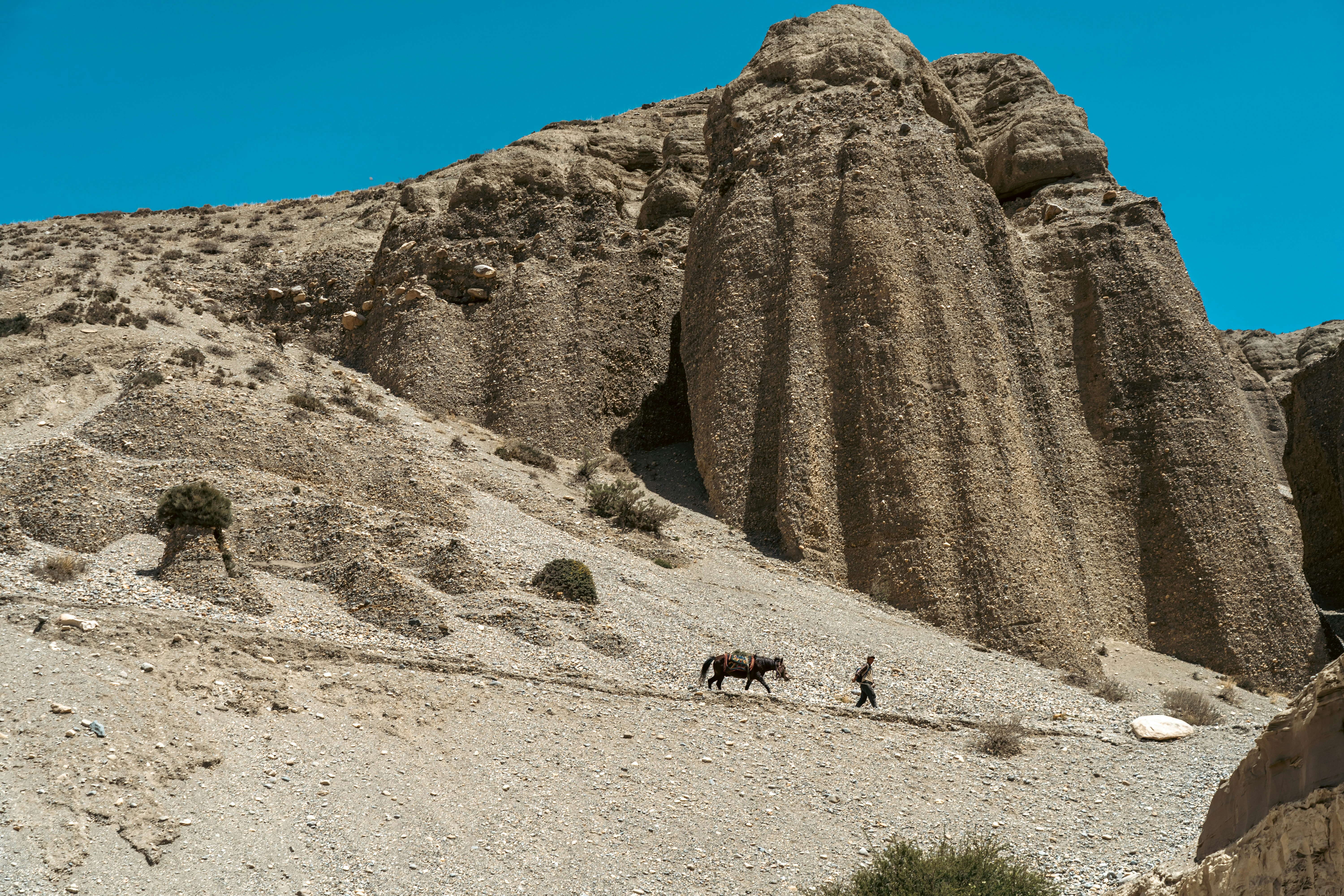 a group of people walking on a dirt road between large rocks