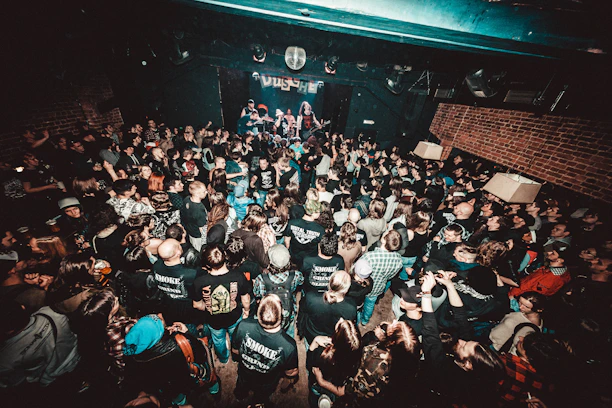 A lively two-story rock bar interior with a balcony full of excited concertgoers.