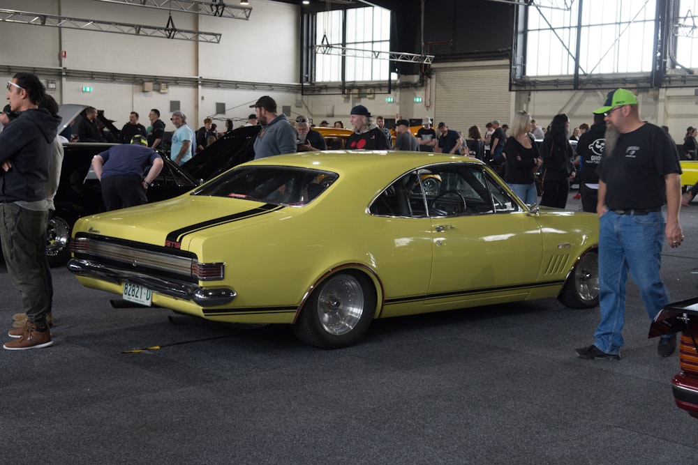 a yellow car parked in a building with people around it