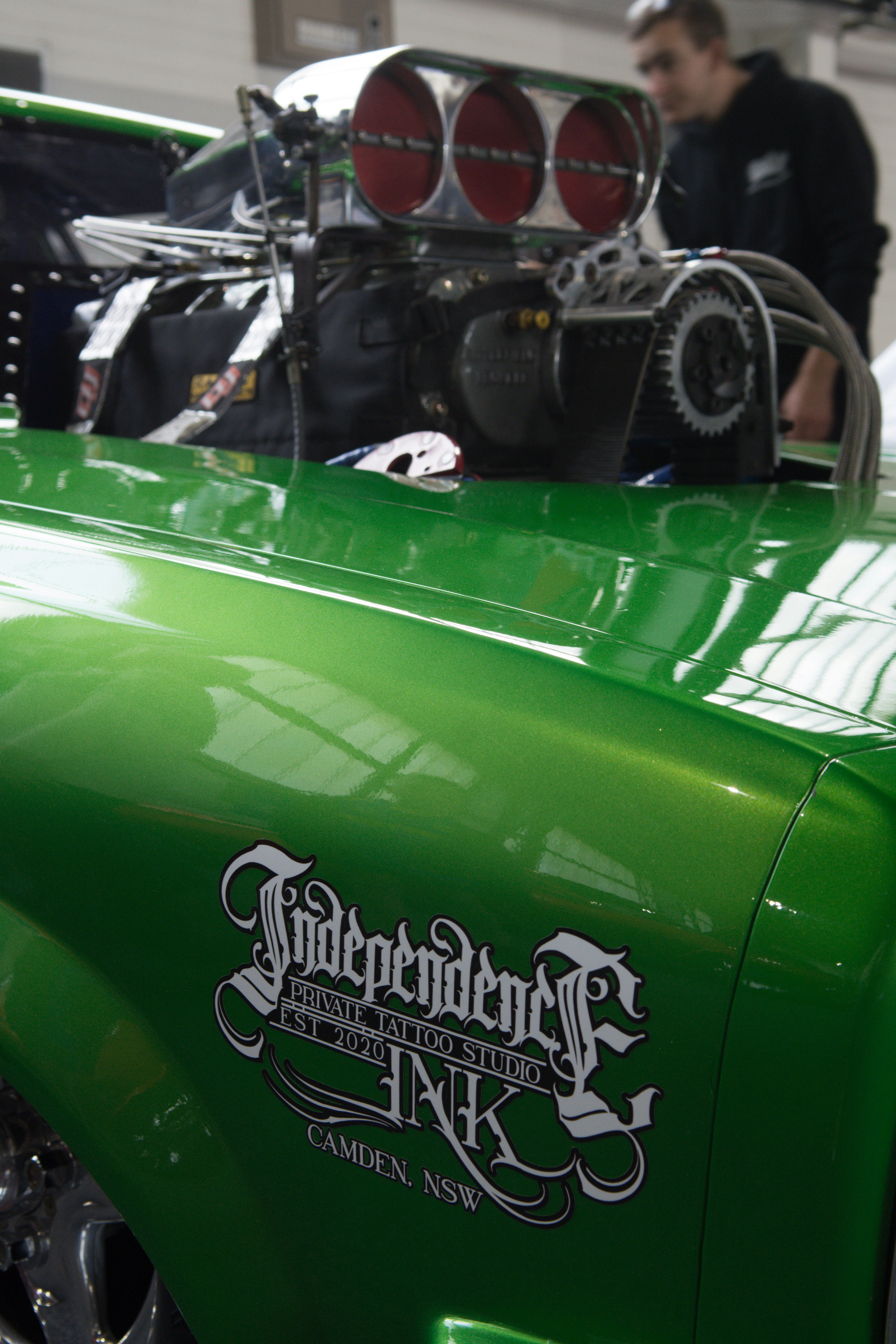 Un coche verde con una persona parada detrás de él