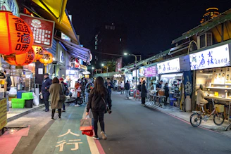 A vibrant Asian street market glowing with lanterns and busy with locals and tourists.