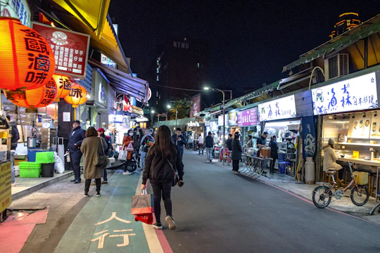 A lively street market at dusk with colorful stalls and glowing lanterns.