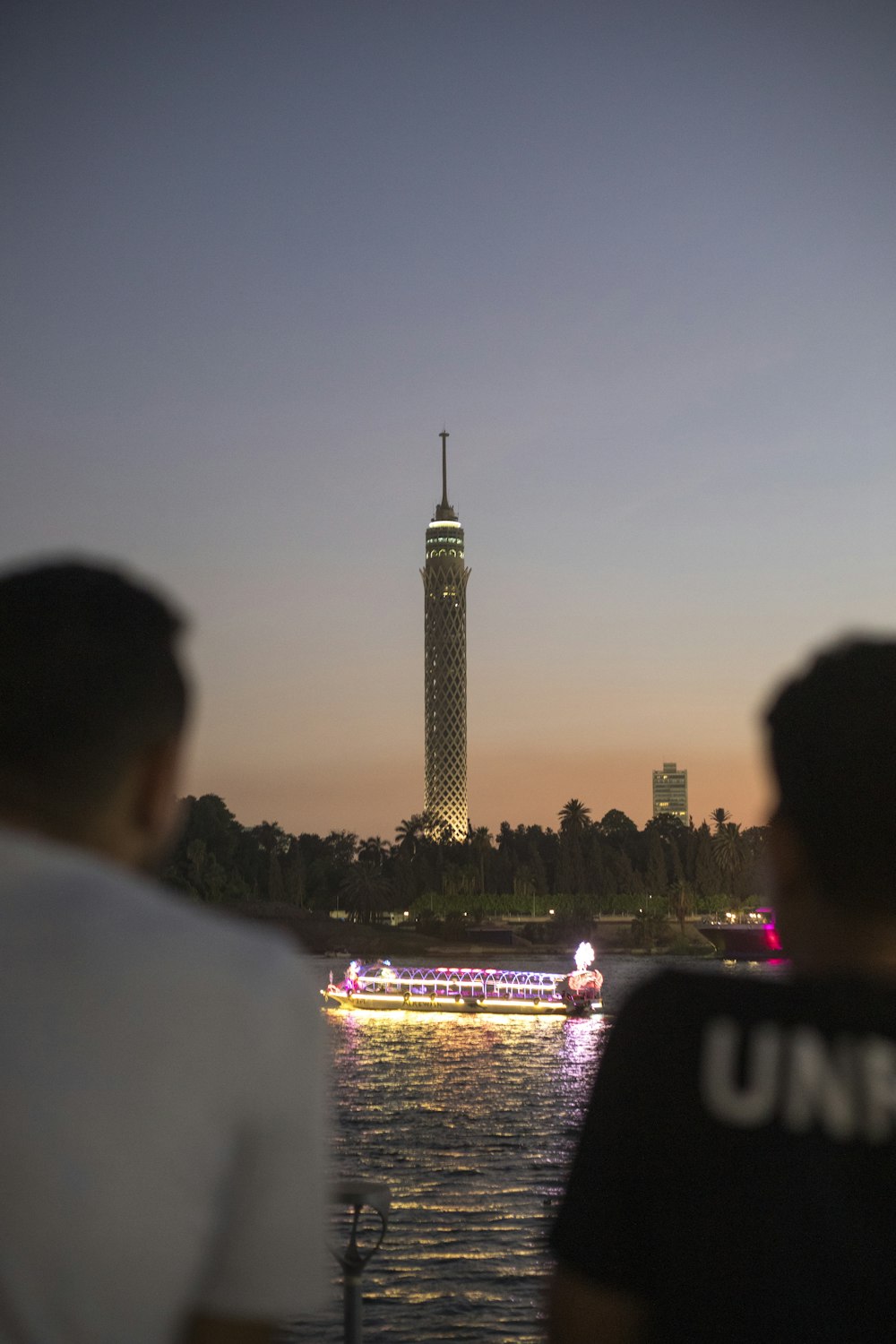 a group of people on a boat in front of a tall tower