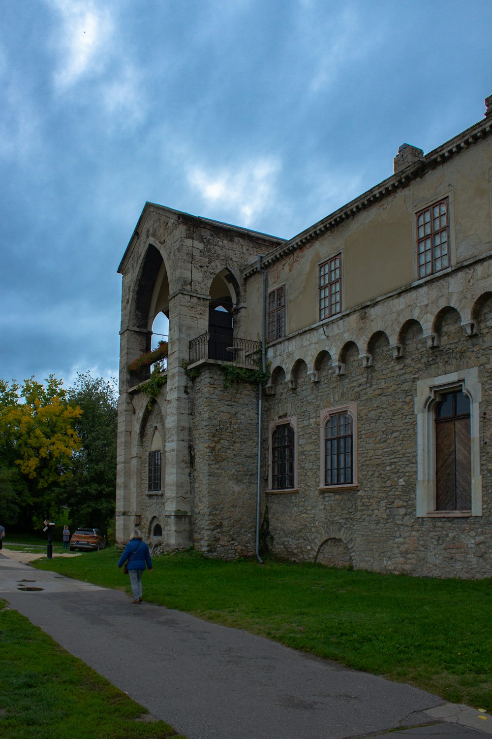 a person walking in front of a stone building with Pluscarden Abbey in the background