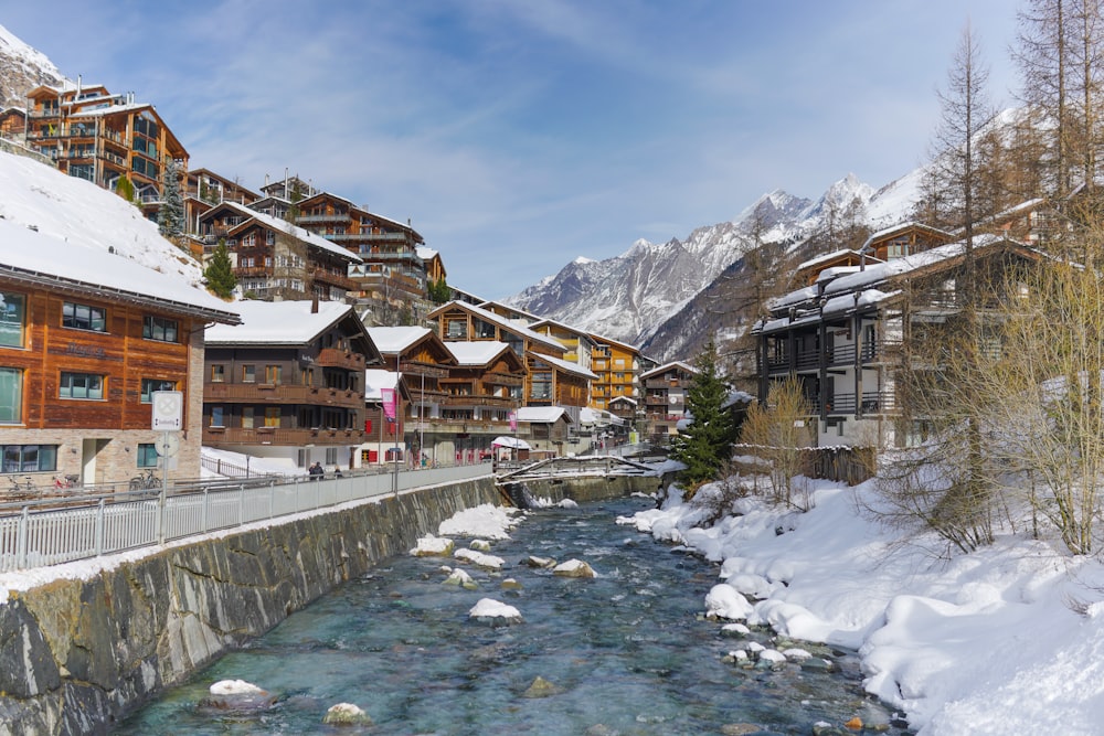 a river with buildings and snow on the banks