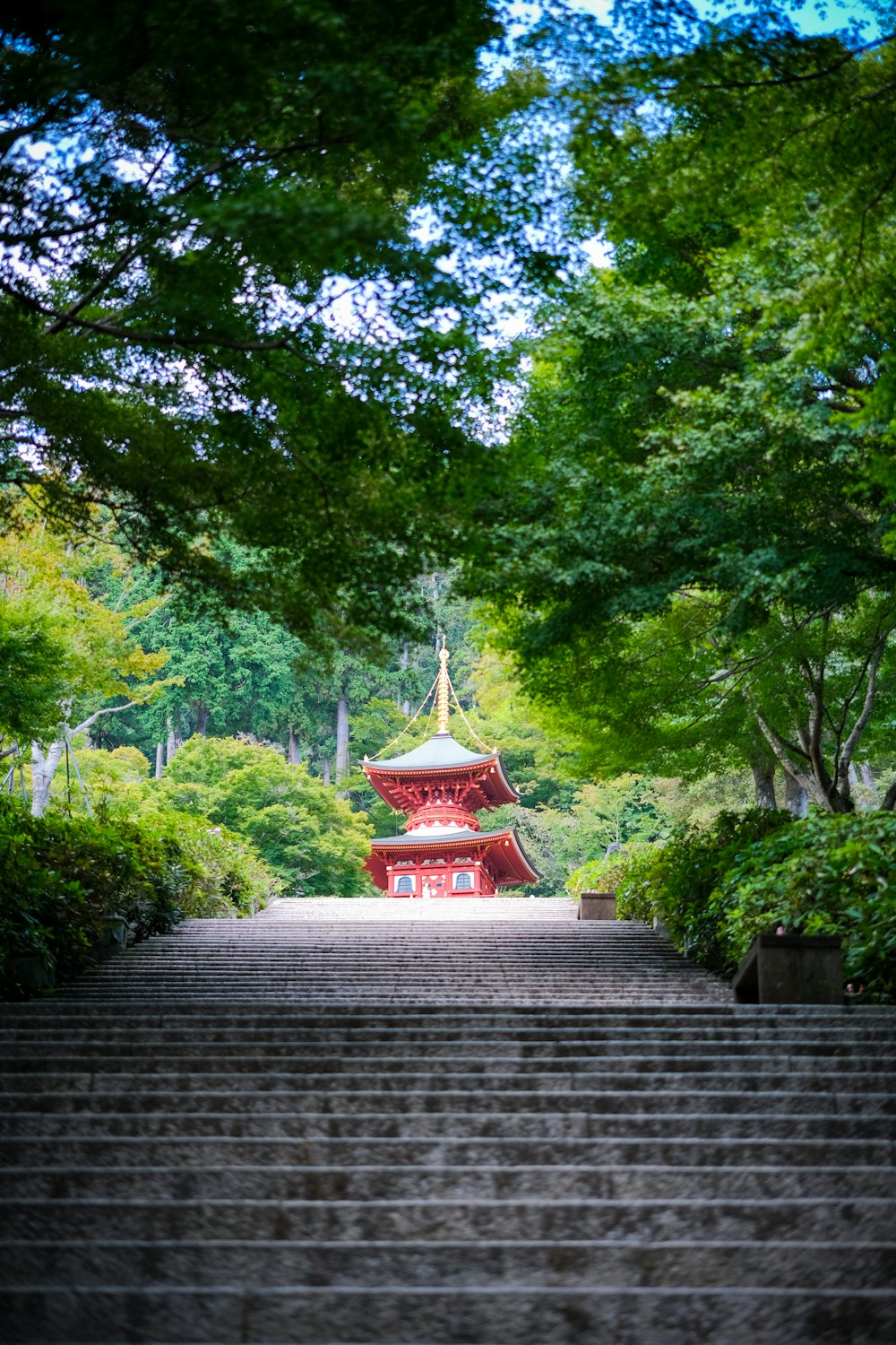 a red pagoda with a pointed roof surrounded by trees