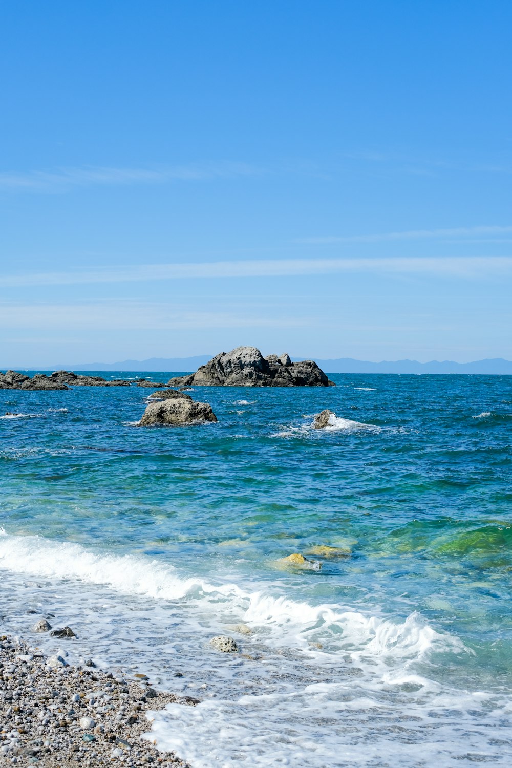 a rocky beach with a large body of water in the background