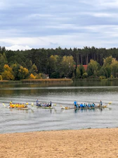 A focused dragon boat coach guiding a team during a morning practice on calm water.