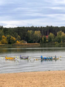 A focused dragon boat coach guiding a team during a morning practice on calm water.