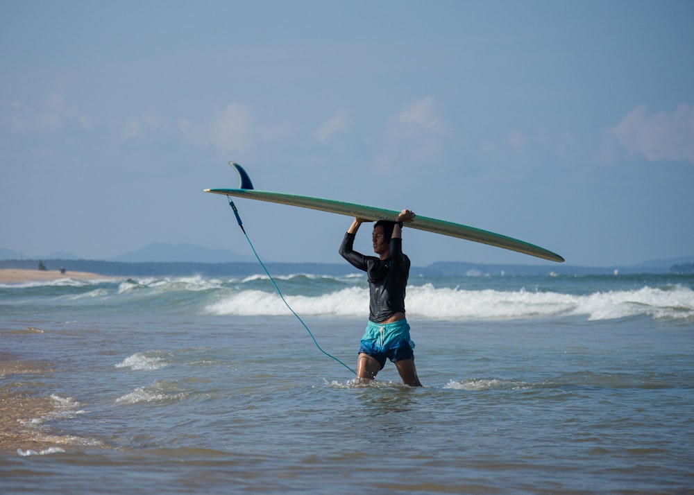 a man carrying a surfboard in the ocean