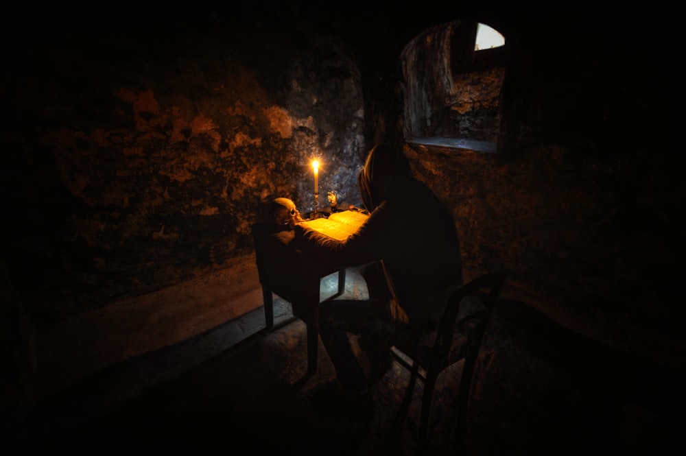 a person sitting in a cave with a fire in their hand