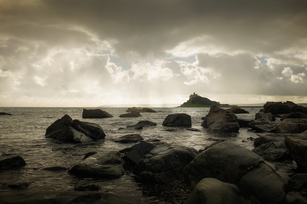 a rocky beach with a large body of water in the background