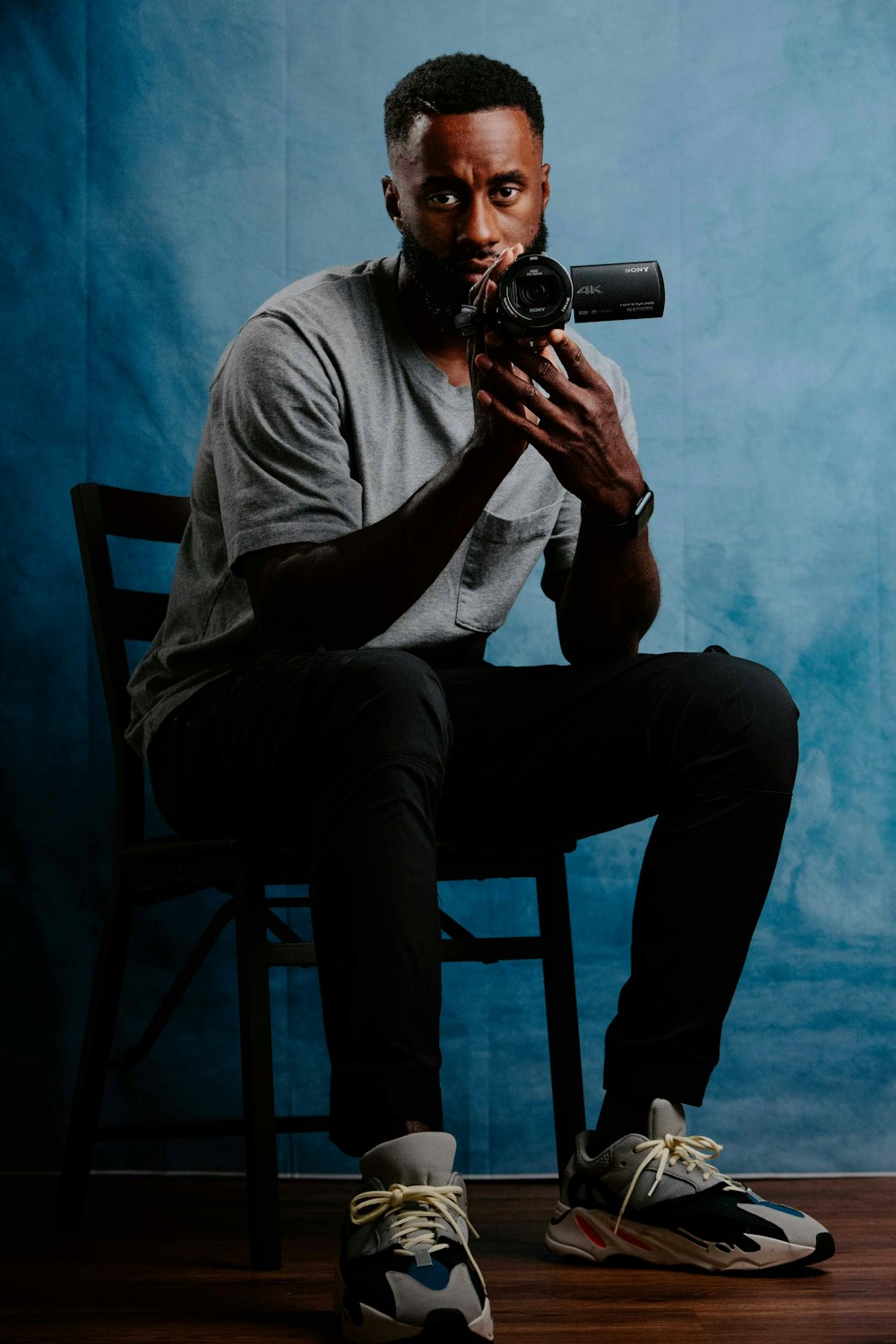 a man sitting in a chair holding a camera up to his face