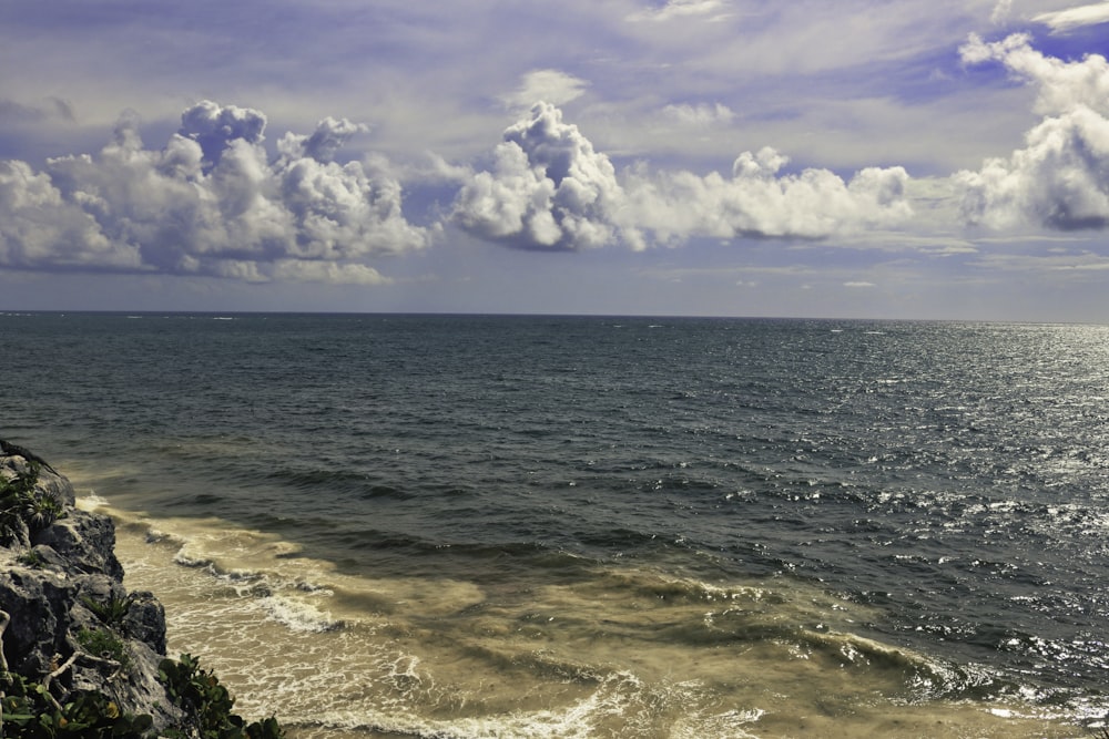 a body of water with rocks and a cloudy sky