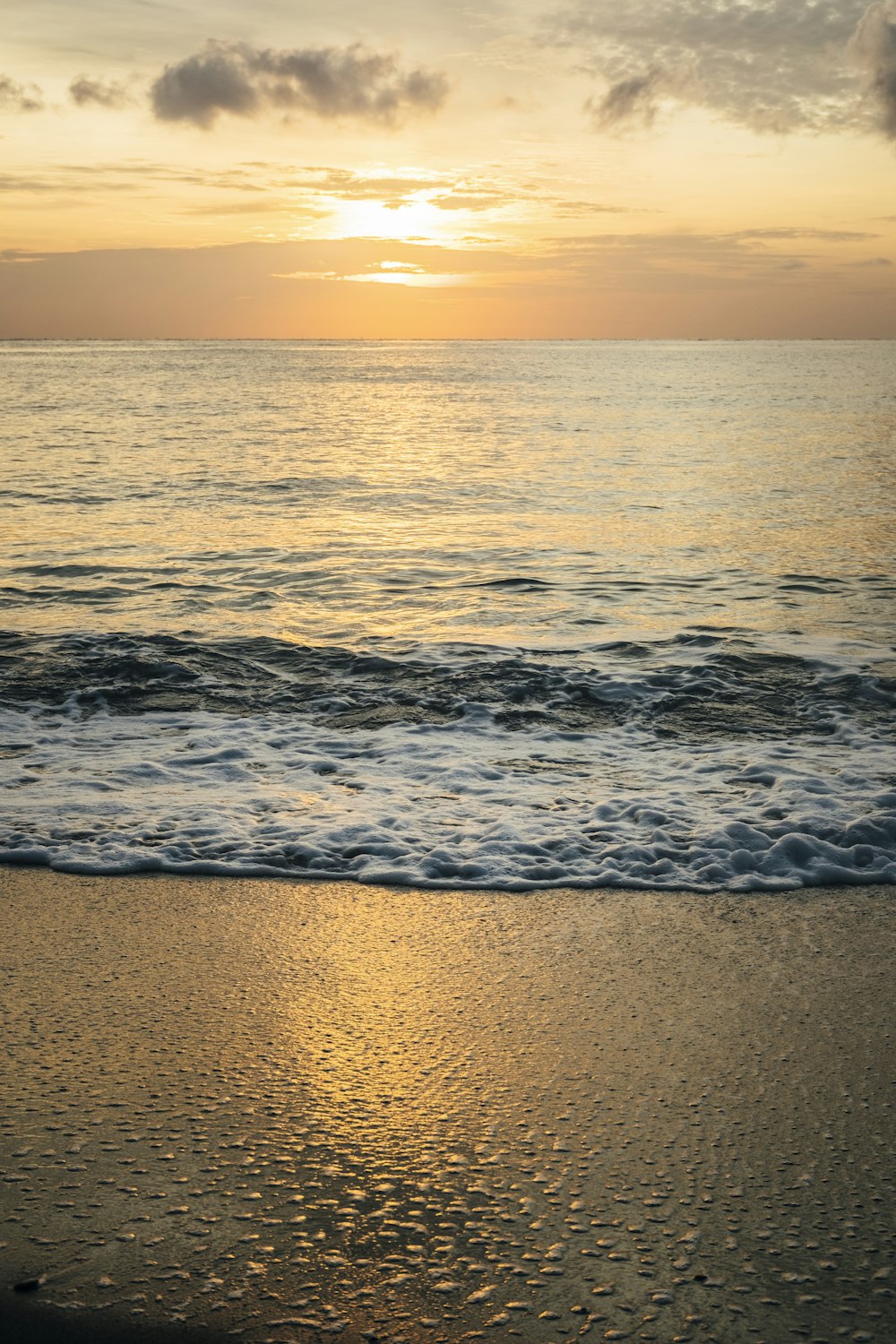 a beach with waves and a sunset