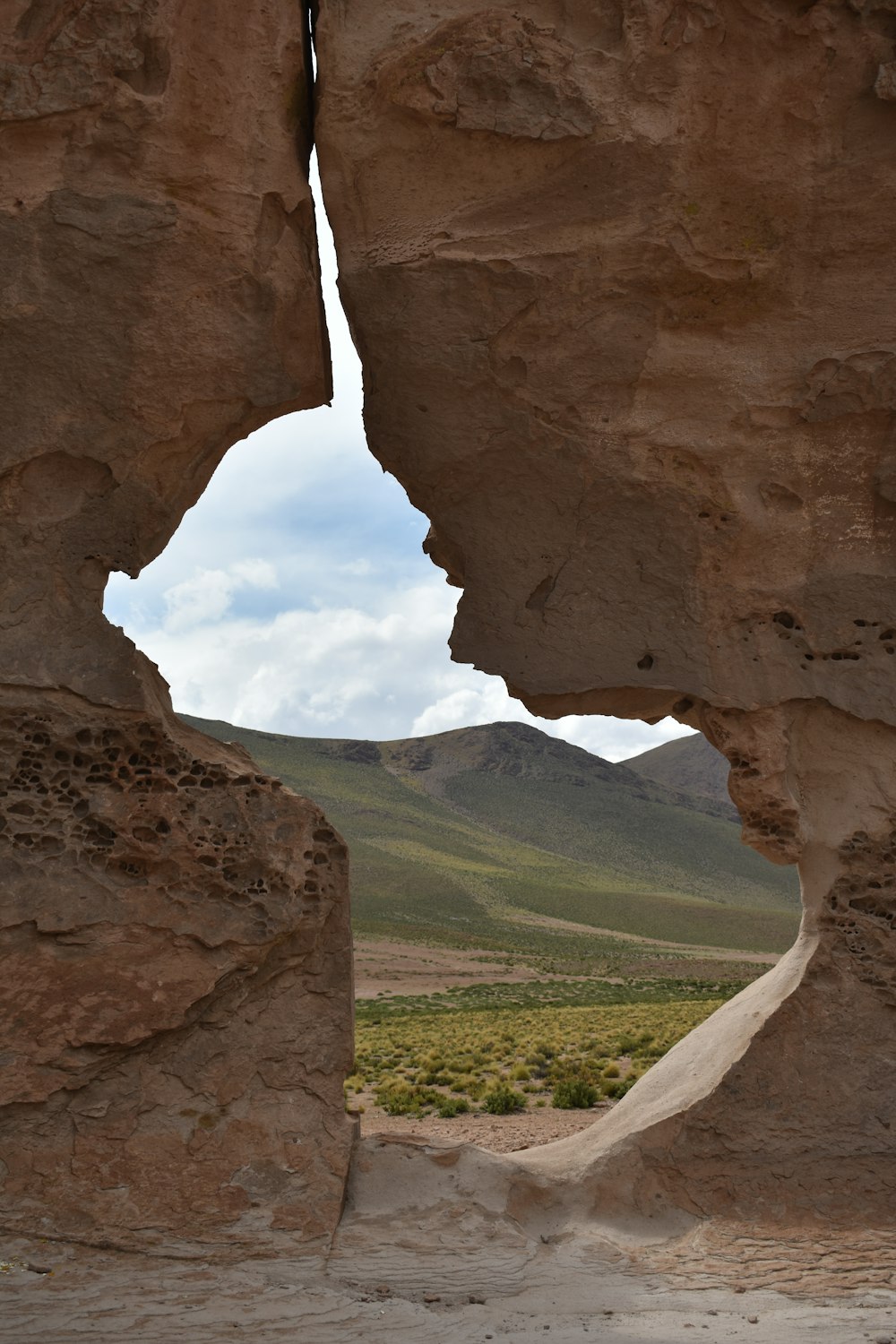 a view of a valley through a rock archway