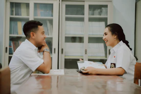 a man and a woman sitting at a table looking at a computer