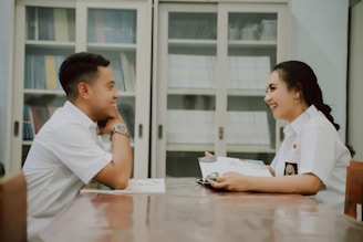 a man and a woman sitting at a table looking at a computer