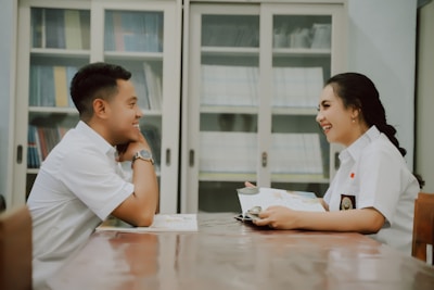 a man and a woman sitting at a table looking at a computer