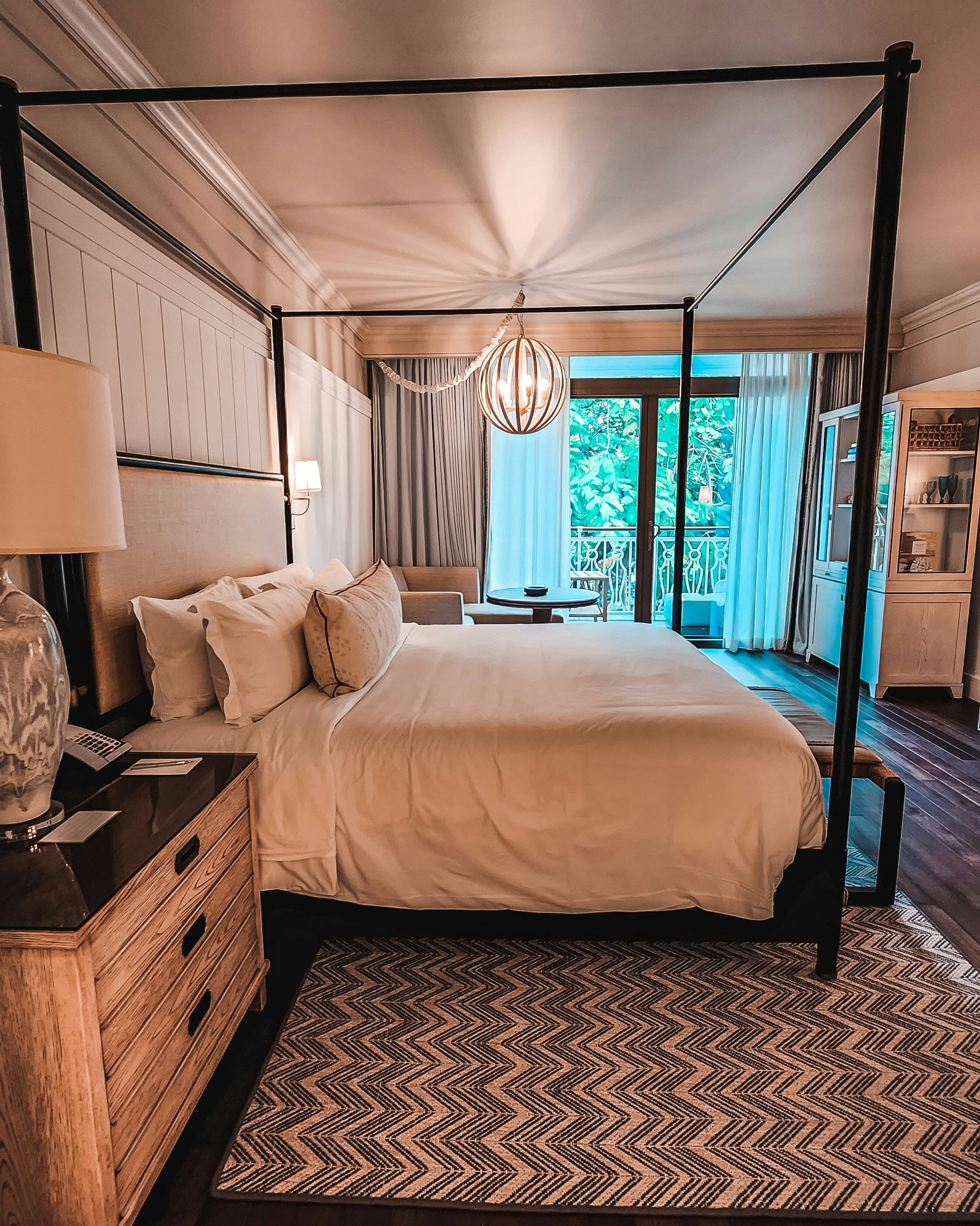 Luxury suite bedroom with king bed, white linens, and private veranda overlooking bush