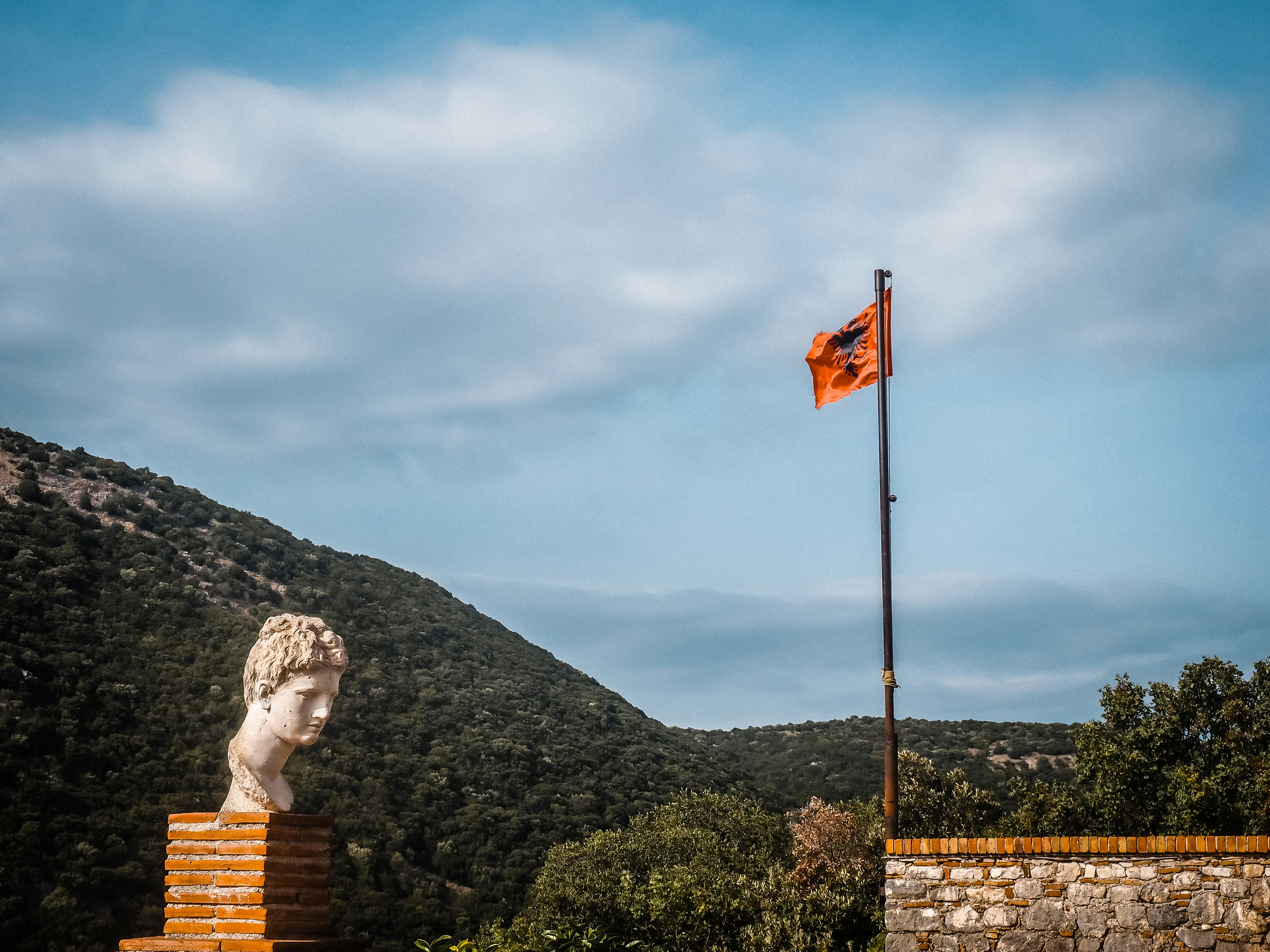 a statue on a pedestal with a flag in the background, 