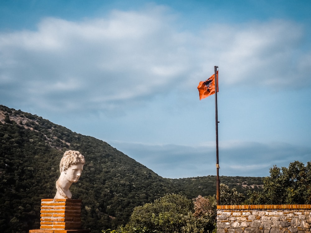 a statue on a pedestal with a flag in the background