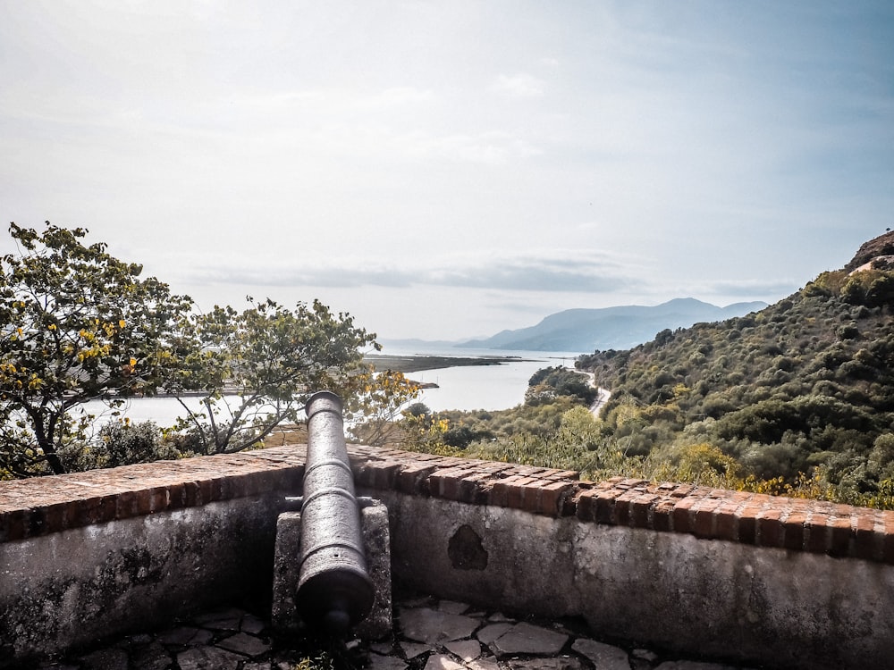 a stone wall with a stone wall and a body of water in the background