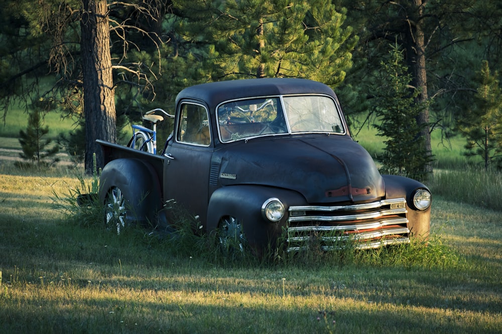 an old truck parked in a grassy field