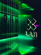 A futuristic interior with green LED lighting casting a vibrant glow. A geometric logo with the word 'LAB' is visible on a reflective wall, alongside vertical light strips creating an immersive atmosphere.