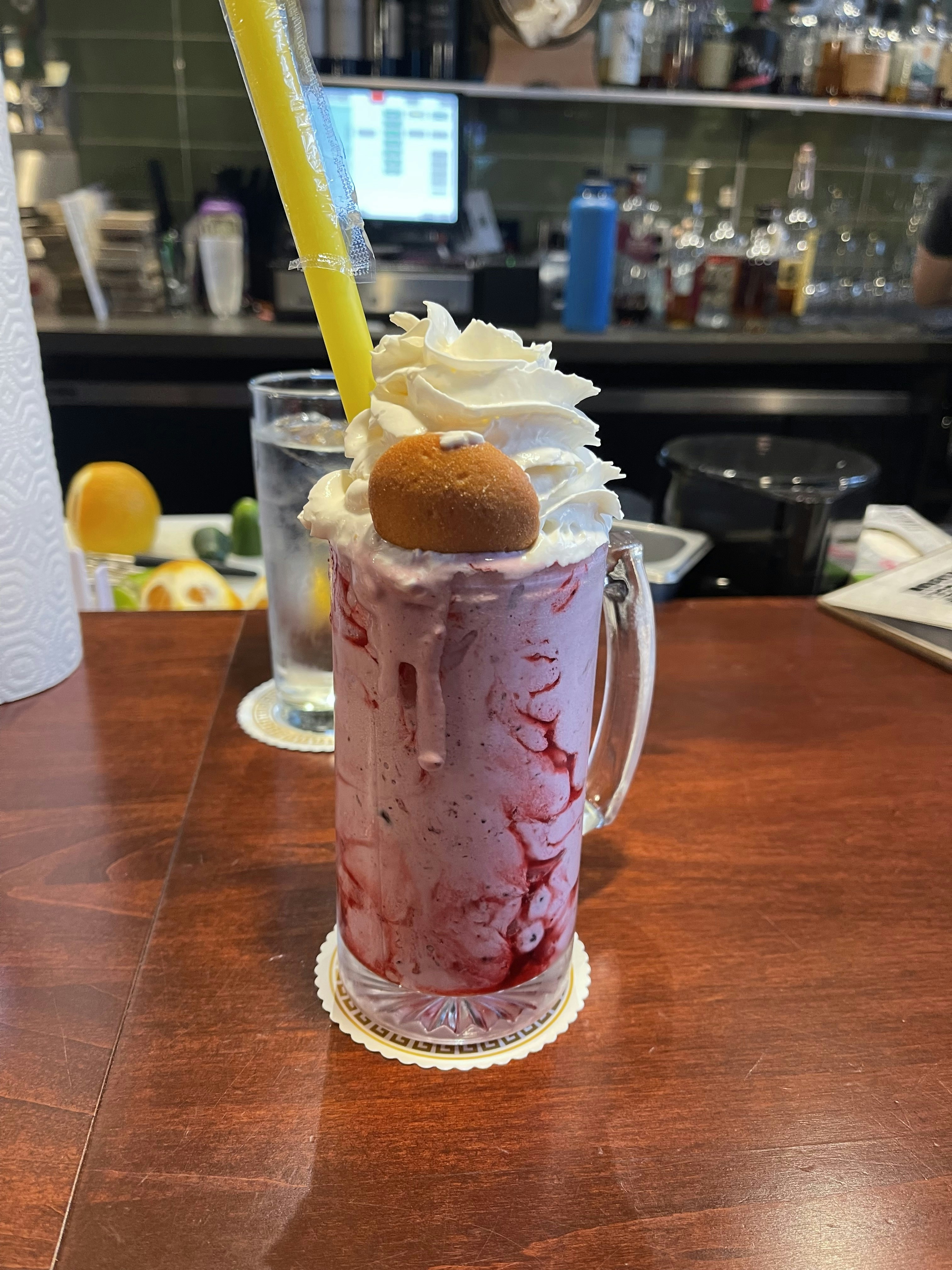 Creamy thick milkshake in tall glass with whipped cream and colorful straw