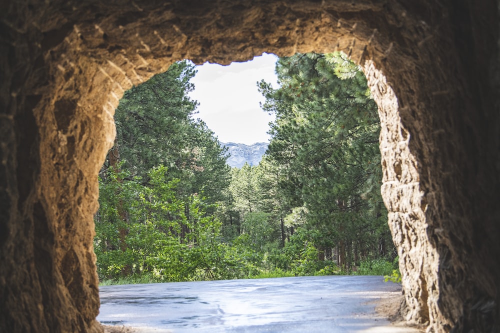 a view through a stone archway at a river and trees