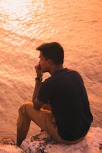 Person reflecting peacefully by the sea during a soft sunset.
