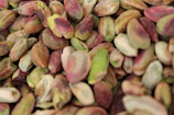 Close-up of glossy, perfectly shelled premium pistachios in a rustic wooden bowl.