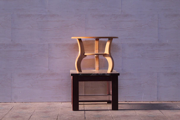 A handcrafted wooden bench stool with a smooth finish placed beside a rustic table