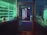 A dimly lit storefront with a glass door displaying a 'Closed' sign. Shelves lined with electronic devices can be seen inside, illuminated by ambient green and blue lighting. Various gadgets and boxes are arranged on the display shelves.