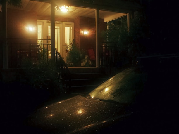 A welcoming front porch of a cozy transitional home with warm lighting at dusk.