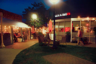 Cheerful customers enjoying meals at an outdoor table under string lights.