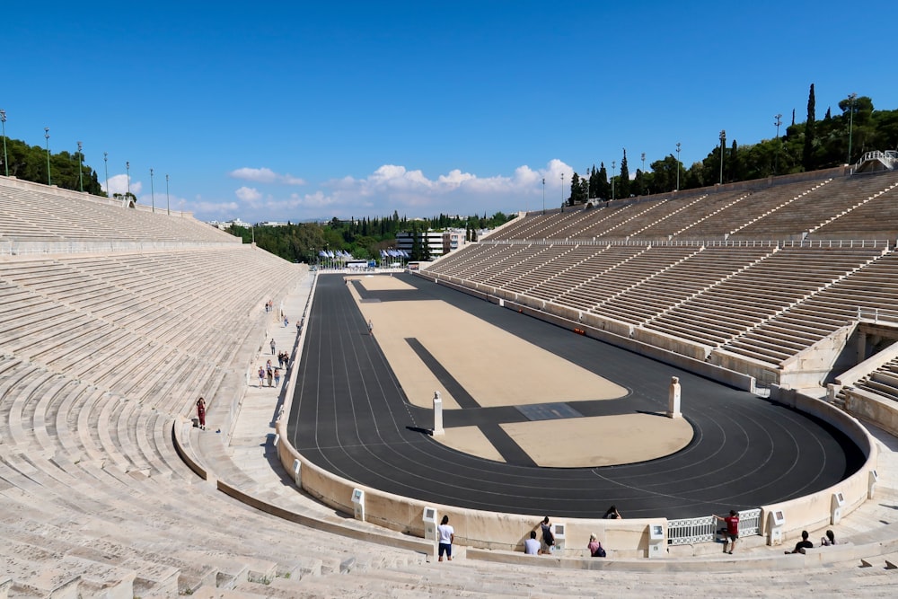 eine große kreisförmige Struktur mit Menschen um sie herum mit dem Panathenaic-Stadion im Hintergrund